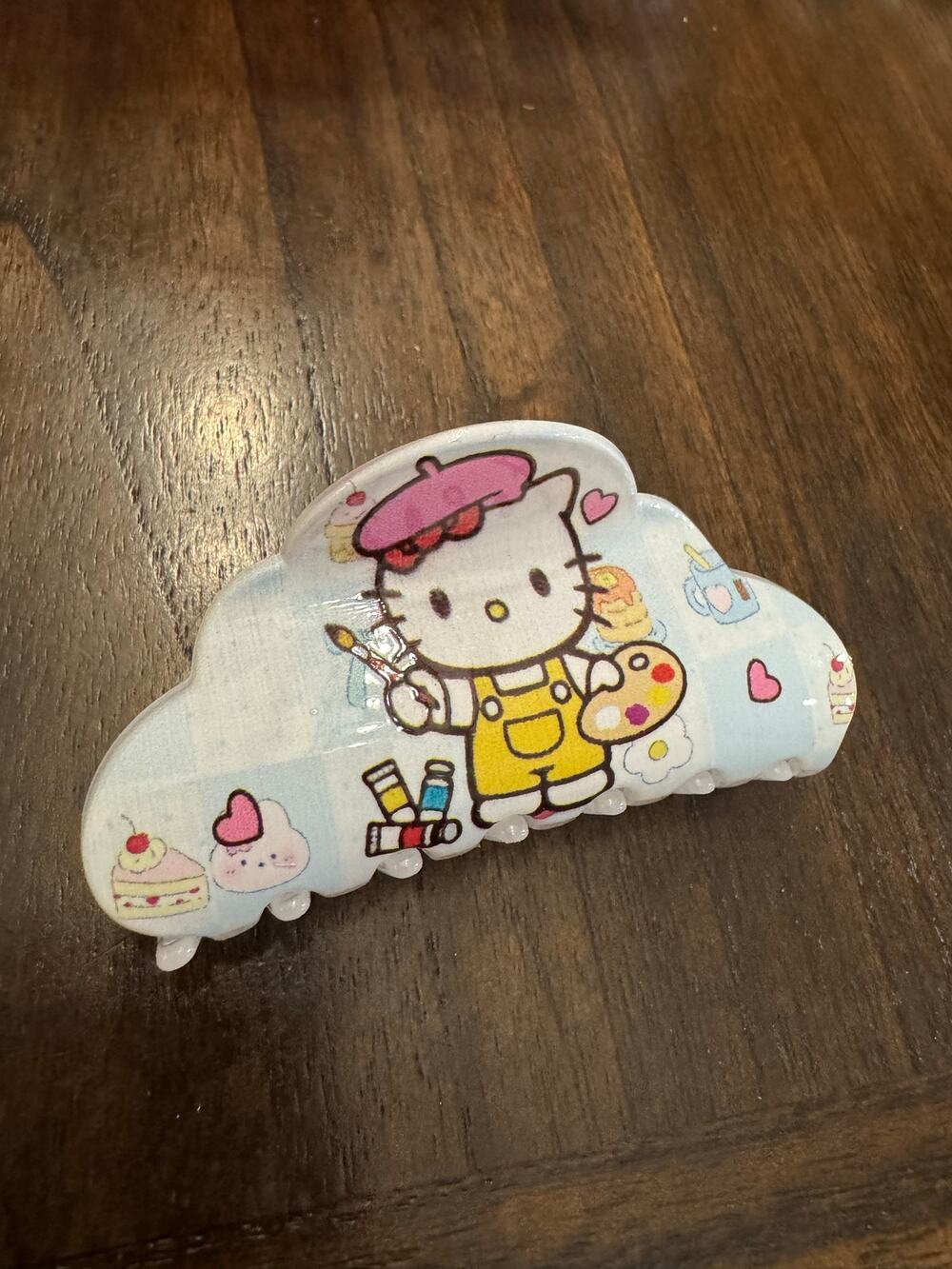 Hello Kitty cloud hair clip holding a paintbrush and palette, around hearts